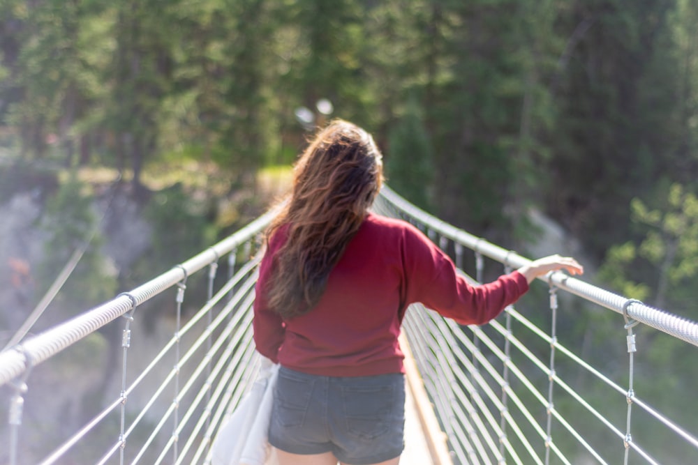 a woman walking across a bridge over a river