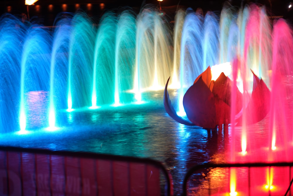 a colorful fountain is lit up at night