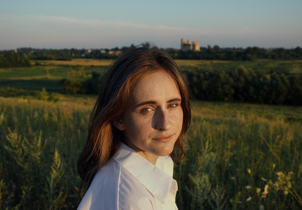 woman in white collared shirt standing on green grass field during daytime