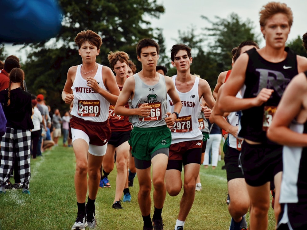 group of men running on green grass field during daytime