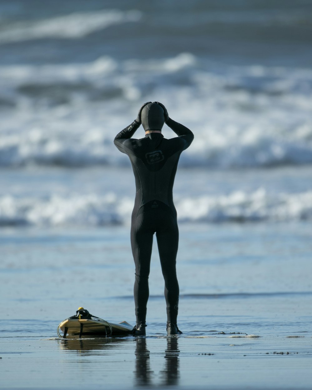 woman in black one piece swimsuit standing on sea shore during daytime