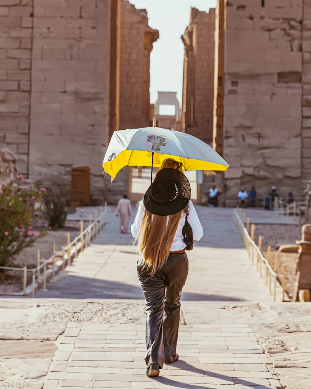 a woman walking down a walkway with an umbrella