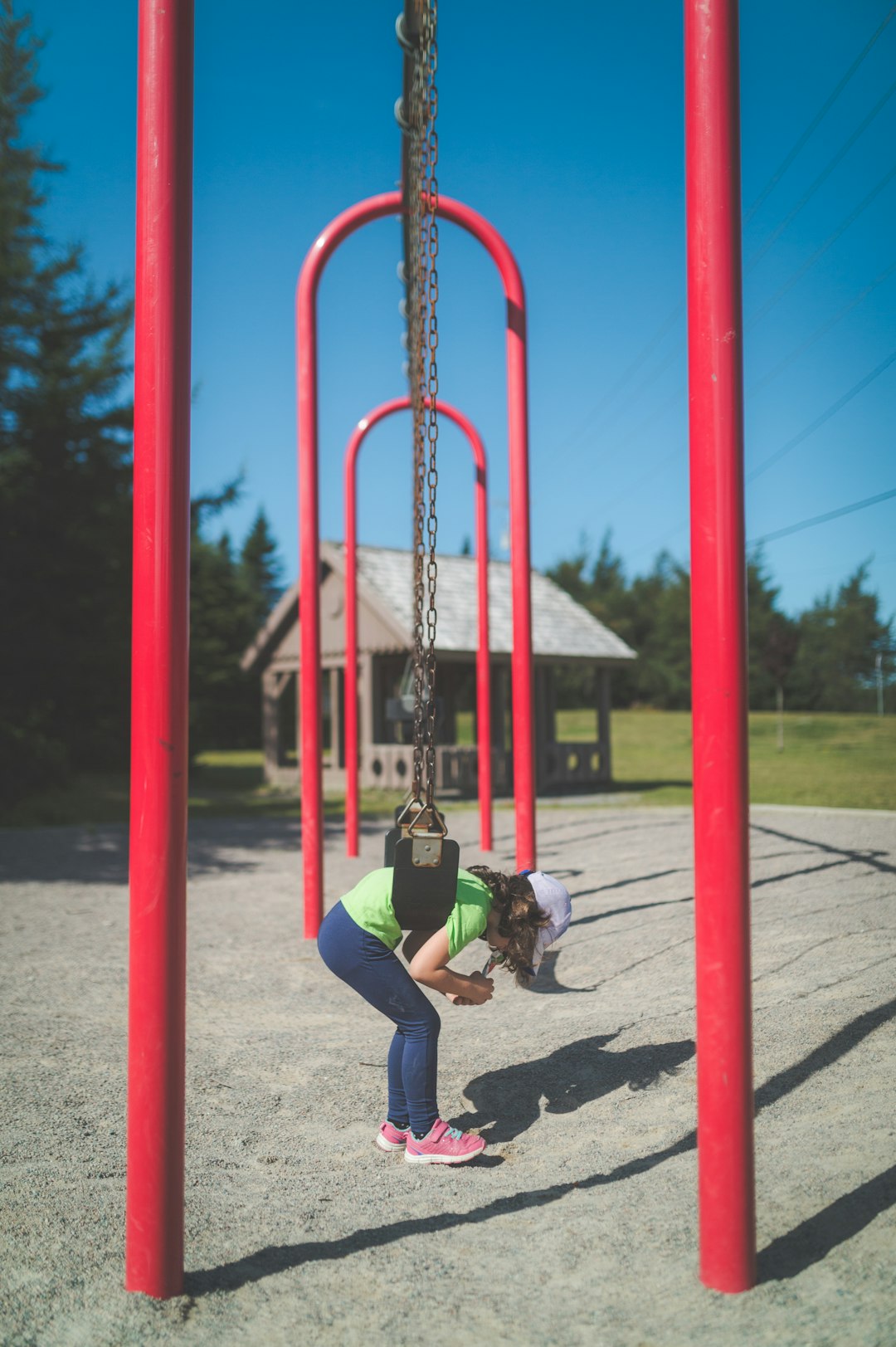 girl in green jacket sitting on swing during daytime