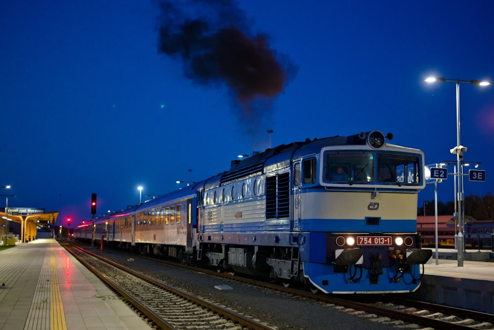blue and red train on rail track during night time