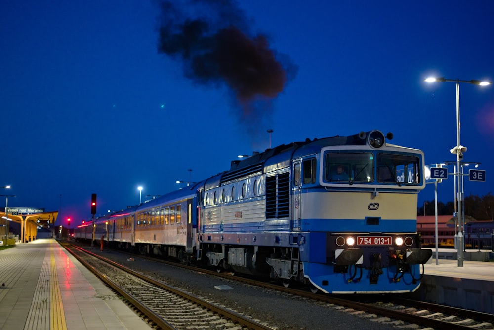 Treno blu e rosso sui binari ferroviari durante la notte