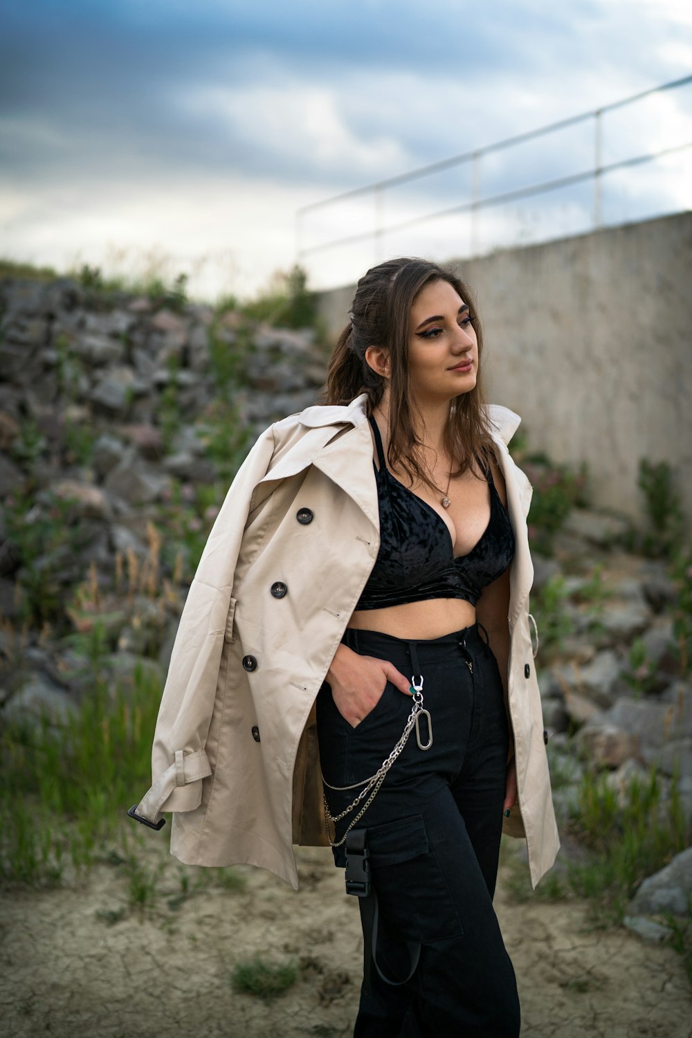 woman in brown coat standing near green plants during daytime