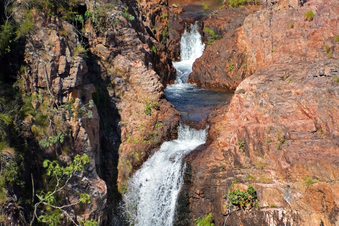 water falls between brown and green rocky mountain during daytime