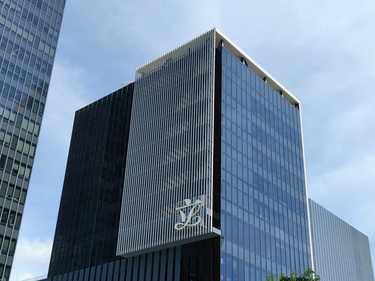 Modern office building with multiple brand logos displayed on its facade.