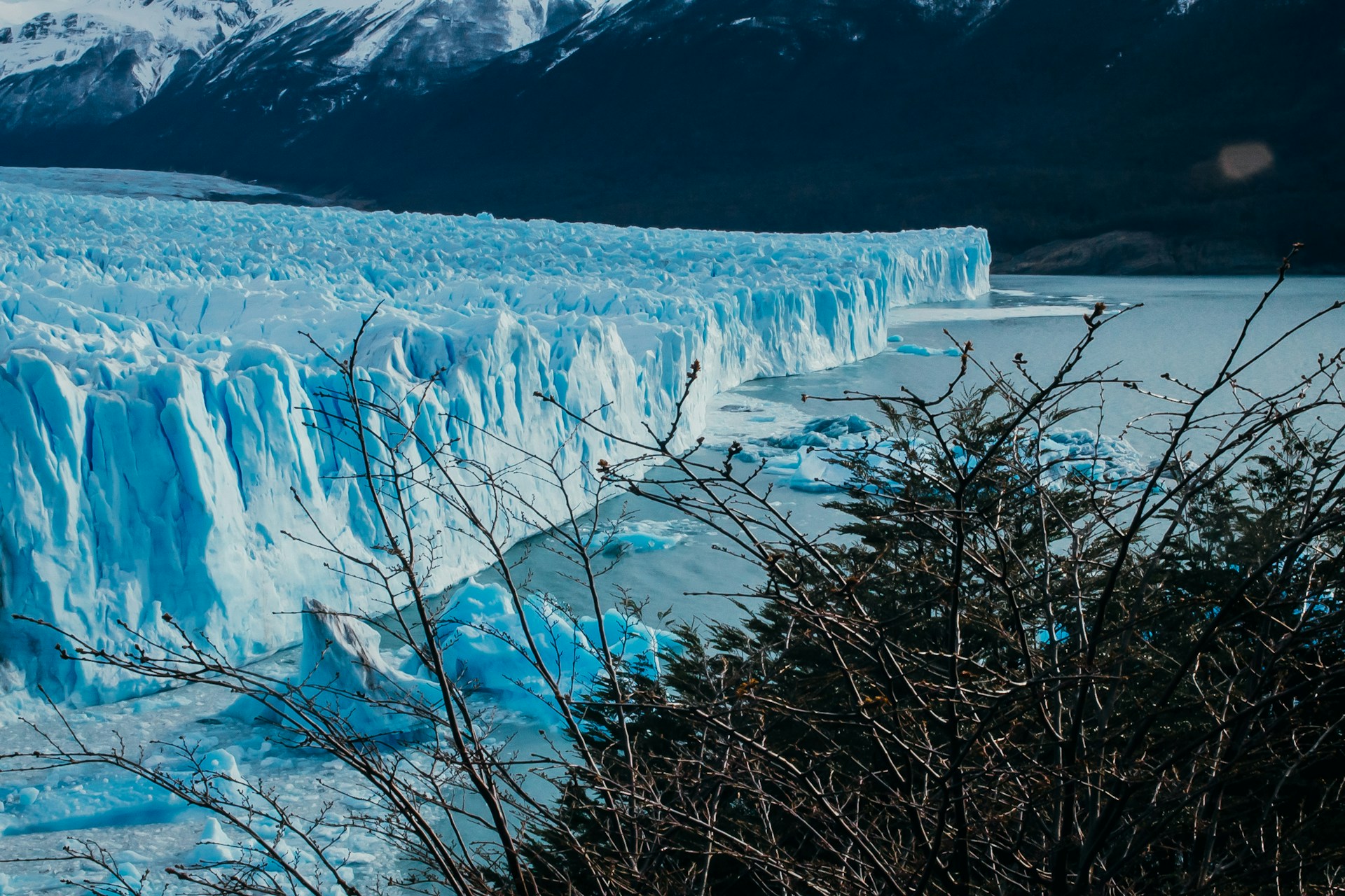 a large glacier with snow capped mountains in the background