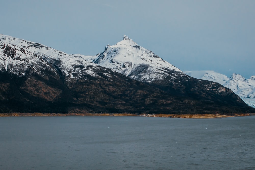 uma grande montanha coberta de neve ao lado de um corpo de água