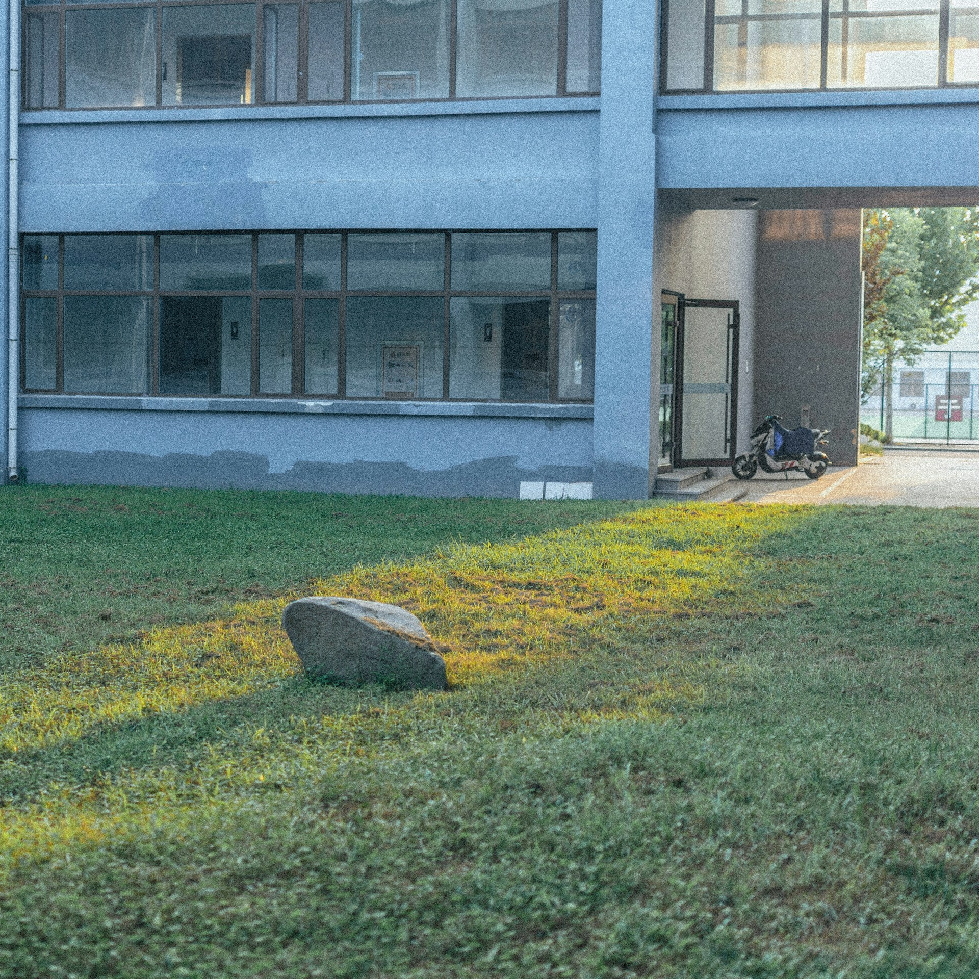 a large rock in the grass in front of a building