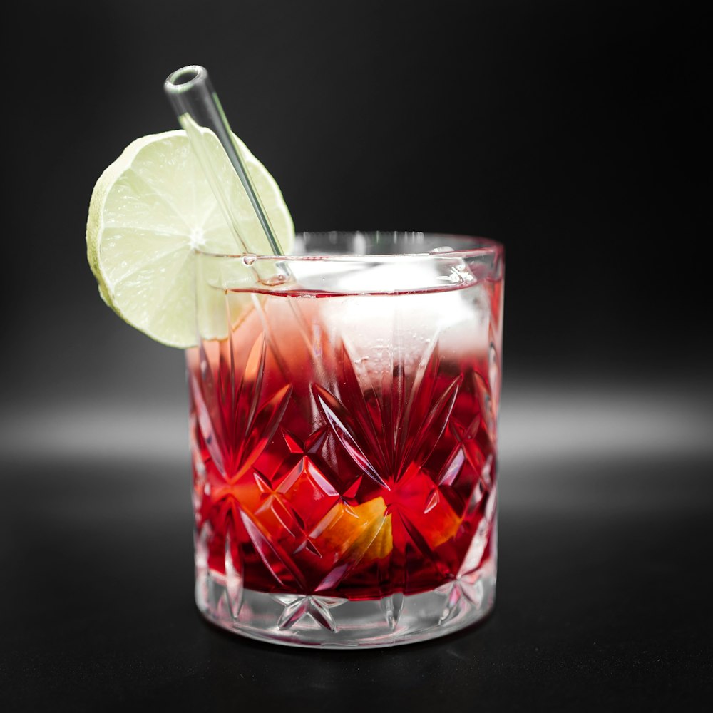clear drinking glass with red liquid and sliced lemon