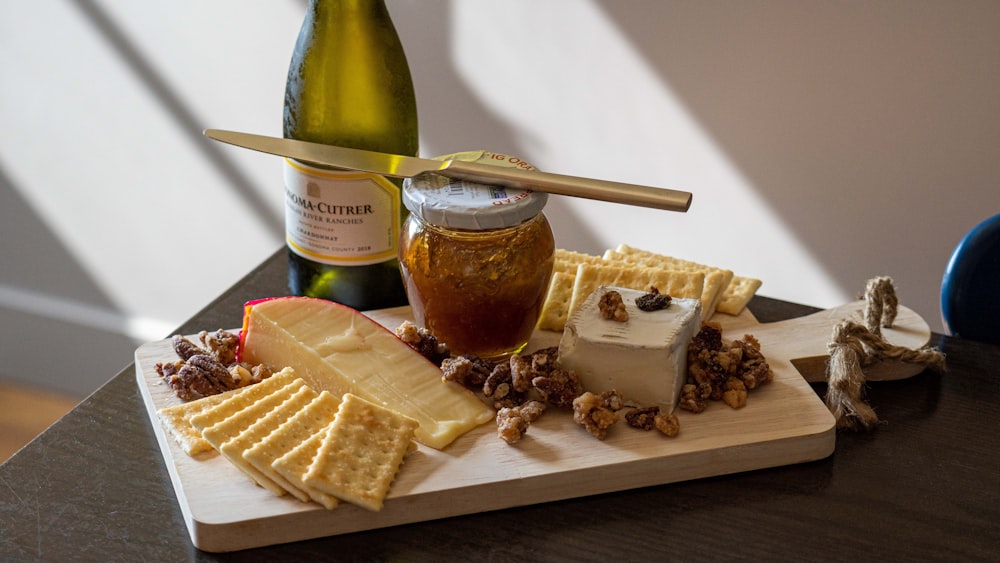 a wooden cutting board topped with cheese and crackers