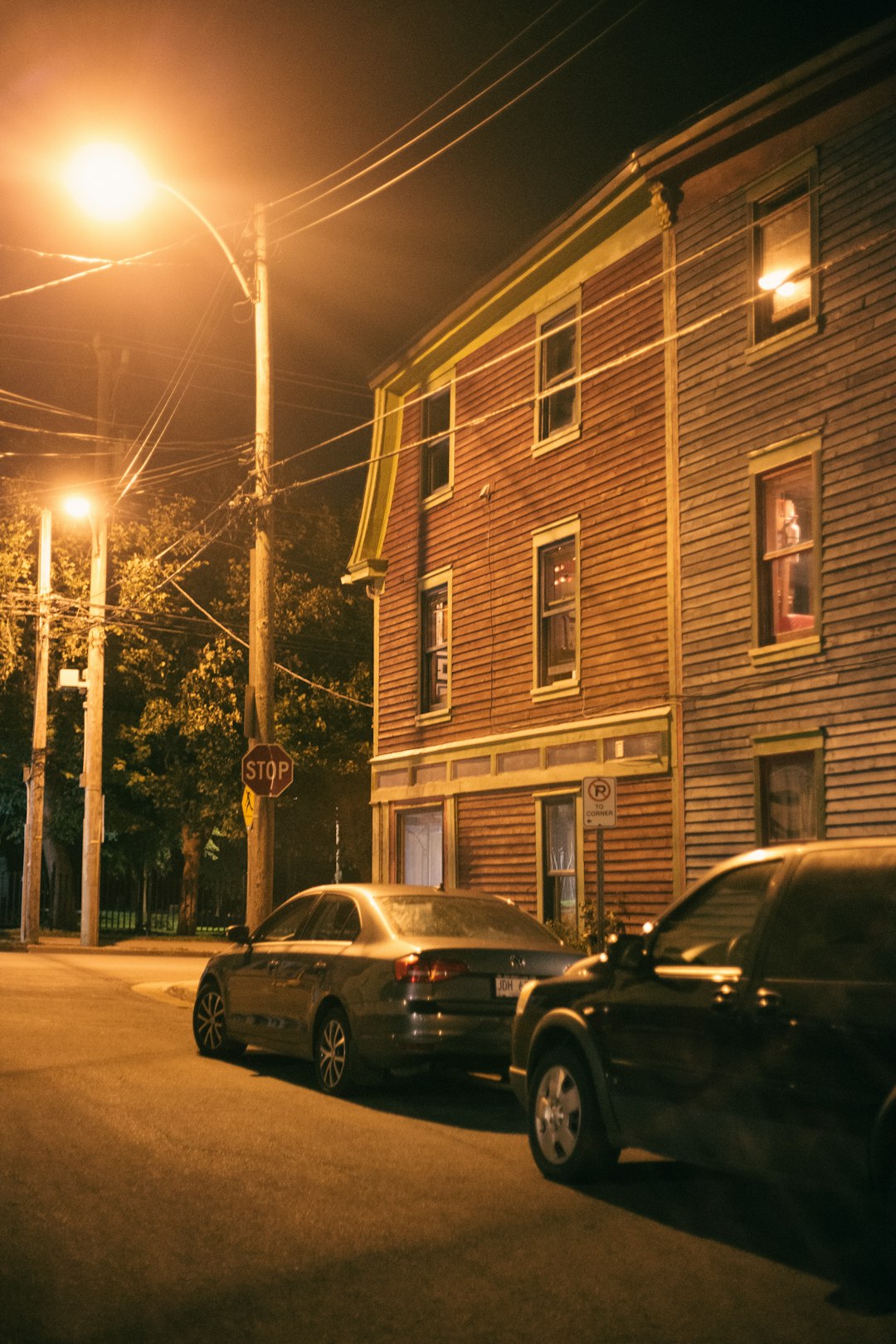 black sedan parked beside brown building during night time