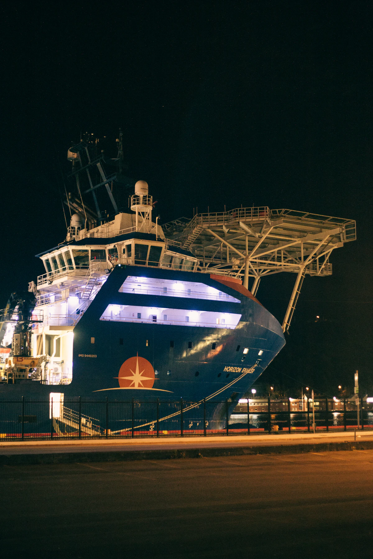 A ship alongside a dock where longshore and harbor workers handle cargo