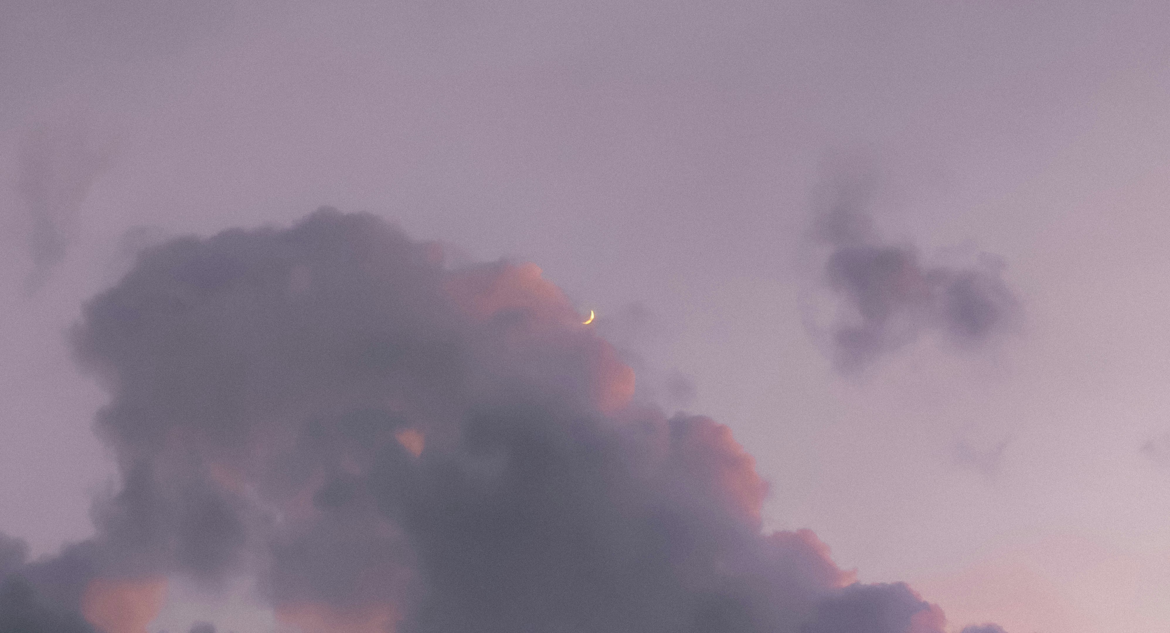 a plane flying through a cloudy sky with a moon in the distance