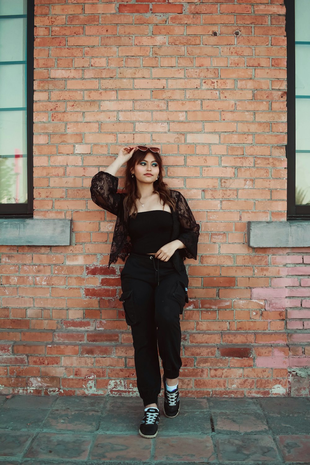 a woman standing in front of a brick wall