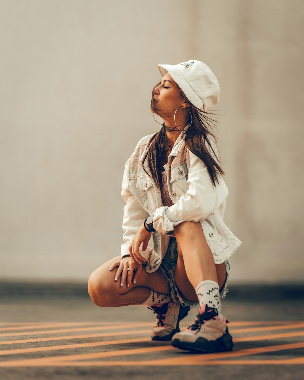 a woman sitting on the ground wearing a white hat