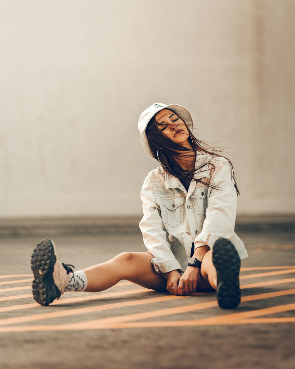 girl in white hoodie and white pants sitting on brown wooden floor