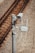 A surveillance camera is mounted on a metal pole beside railway tracks. The pole also has attached electronic equipment with antennas, likely for communication or data transmission. The tracks run parallel on gravel-covered ground.