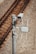 A surveillance camera is mounted on a metal pole beside railway tracks. The pole also has attached electronic equipment with antennas, likely for communication or data transmission. The tracks run parallel on gravel-covered ground.