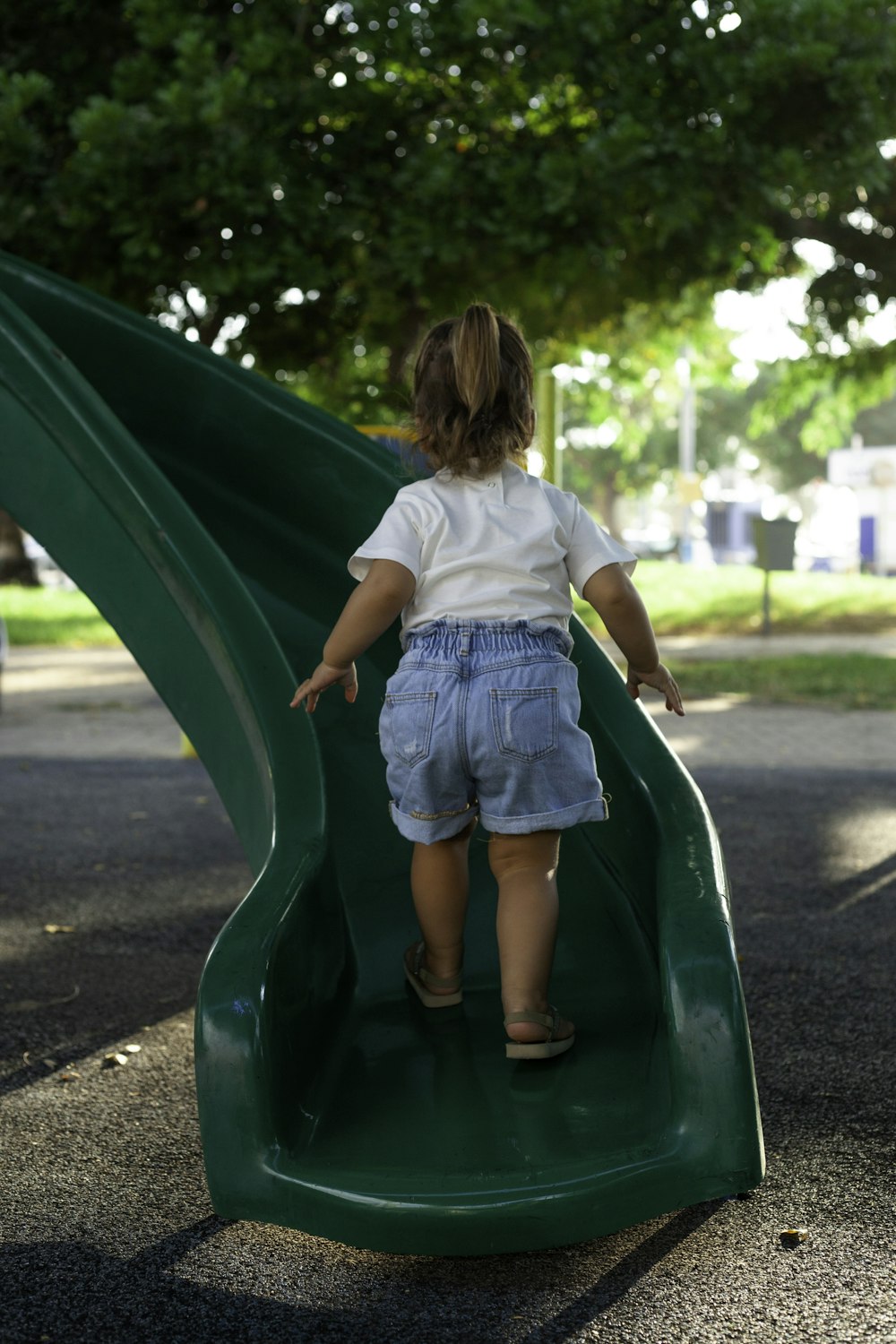a little girl playing on a green slide