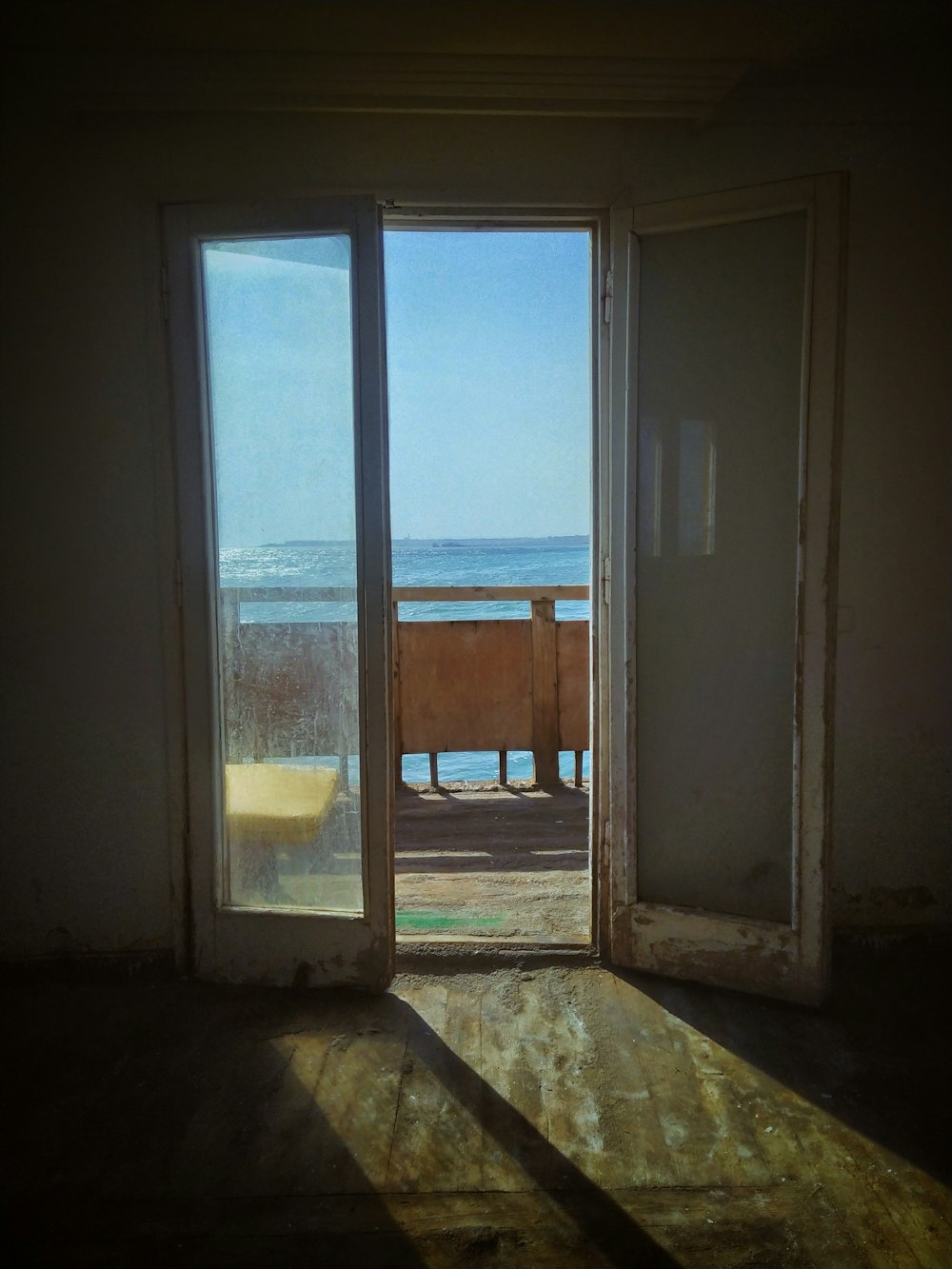 una puerta abierta que conduce a un balcón con vistas al océano