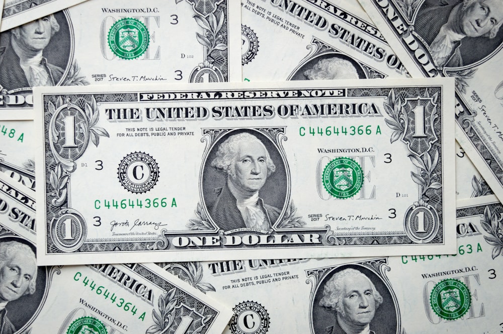 uma pilha de notas de um dólar deitadas umas sobre as outras