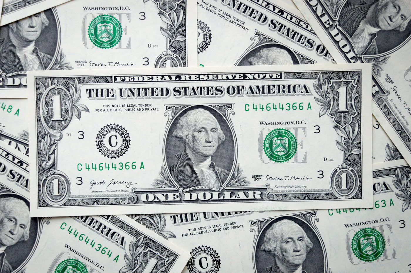 A crisp US one-dollar bill lying on top of other one-dollar bills