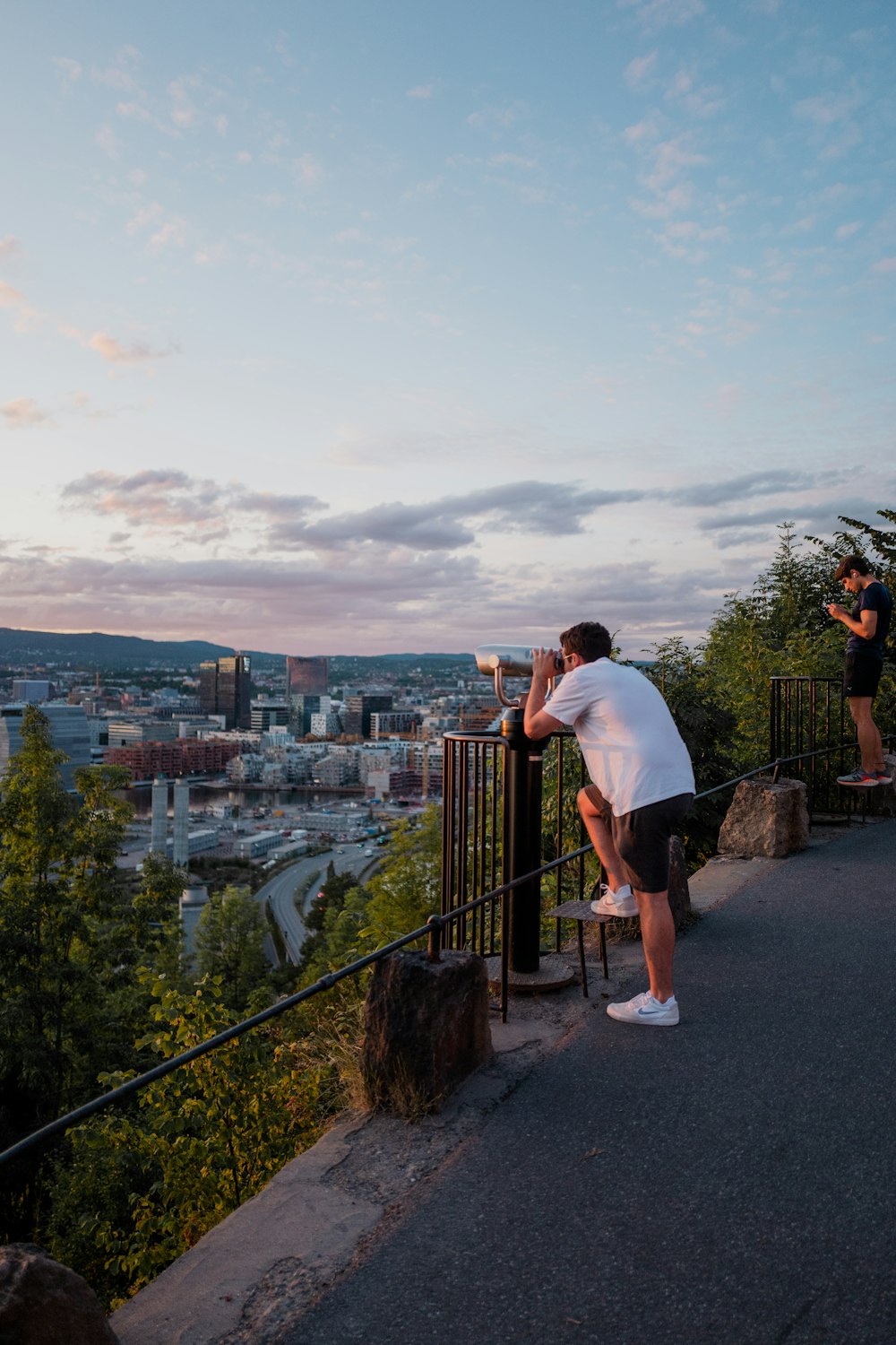 Mann in weißem T-Shirt steht auf dem Dach des Gebäudes und schaut tagsüber auf die Stadt