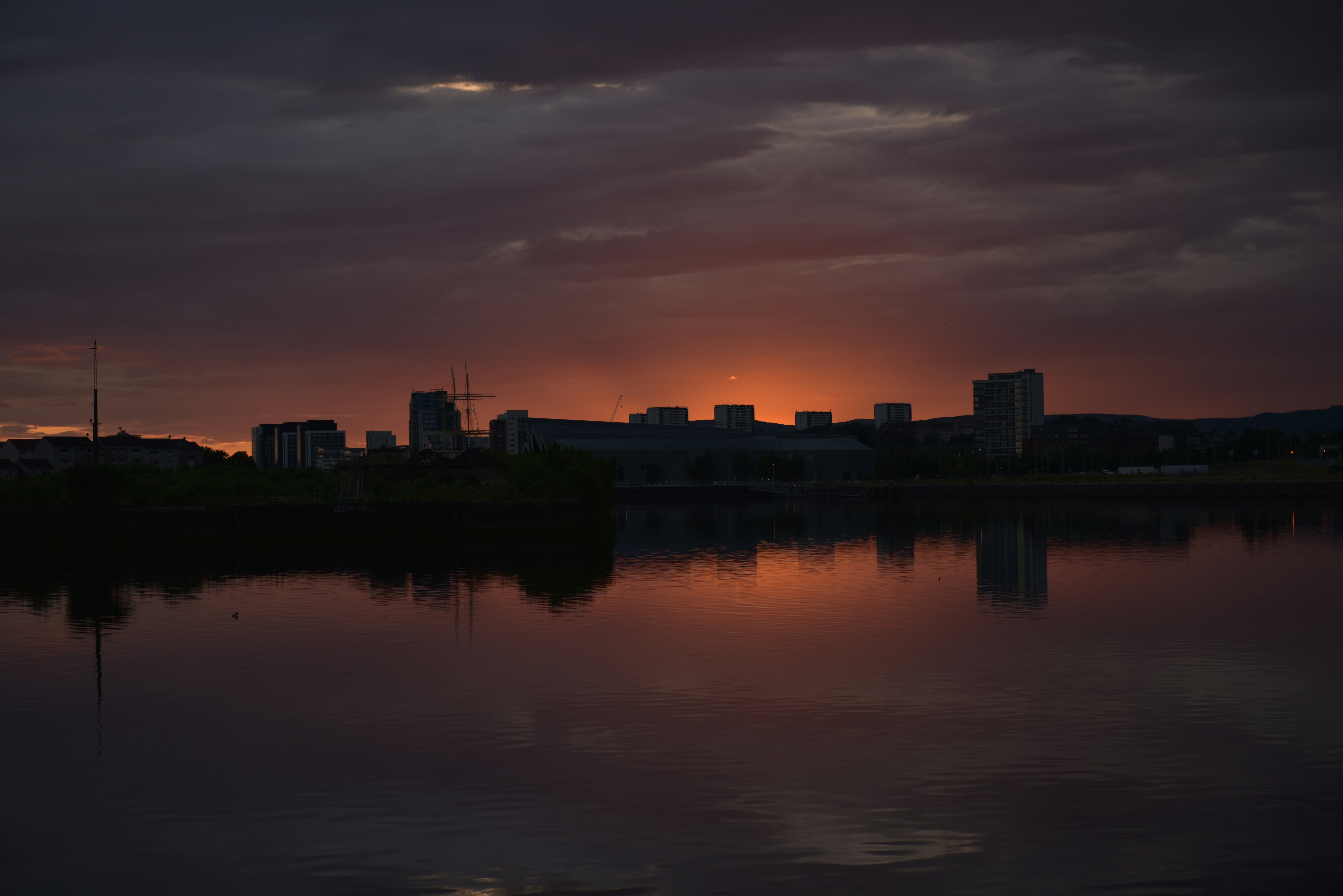 the sun is setting over a city and a body of water