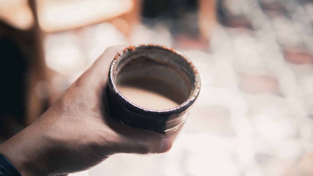 a person holding a cup of coffee in their hand