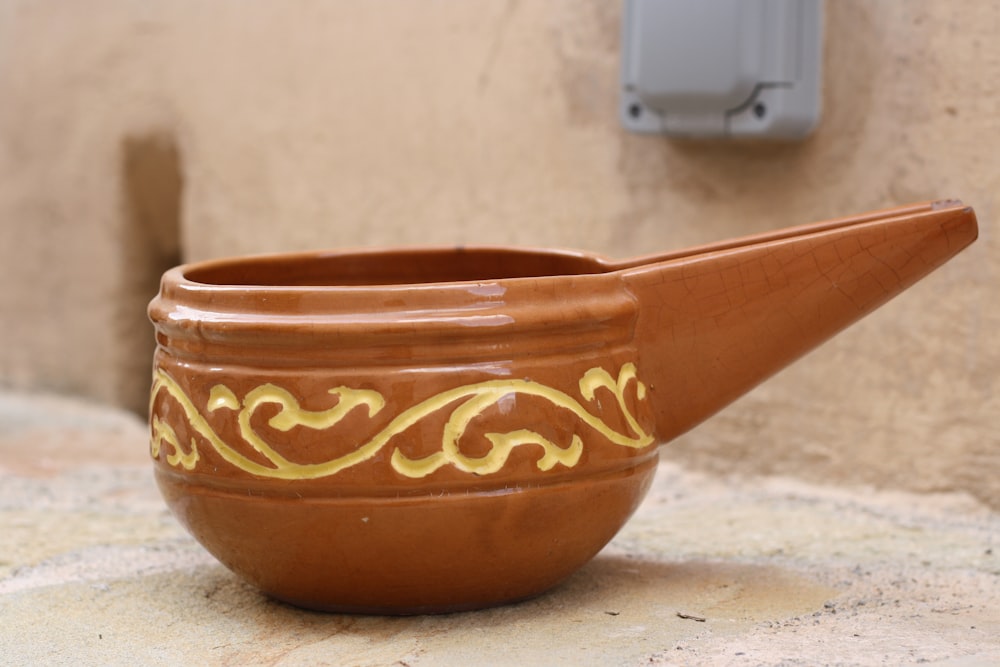 a brown vase sitting on top of a counter next to a wall