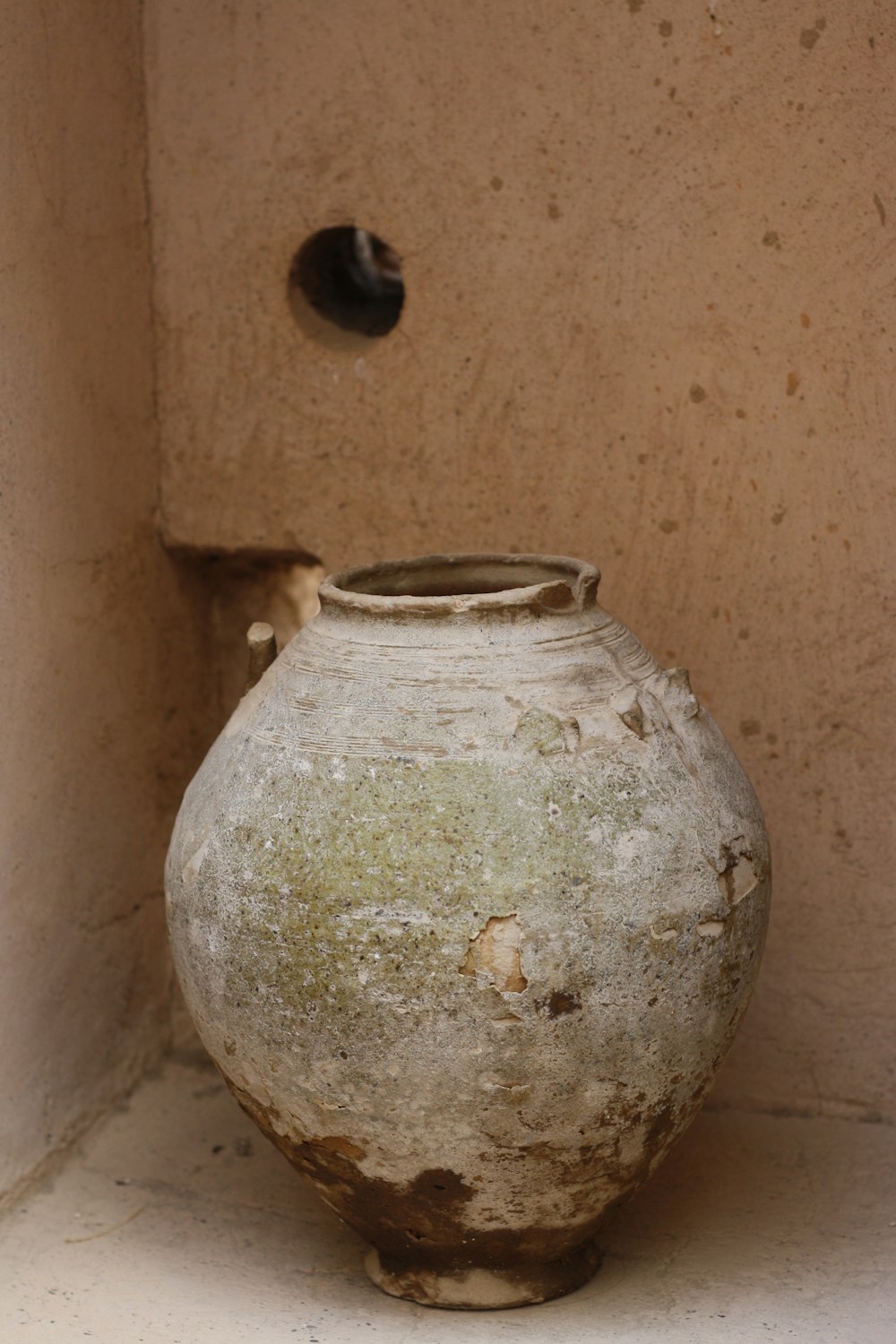 a dirty vase sitting in a corner of a room