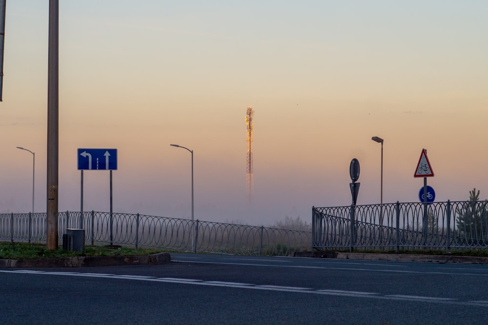 a street with a fence, street lights, and street signs