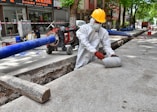 a man wearing a protective suit and a hard hat working on a street
