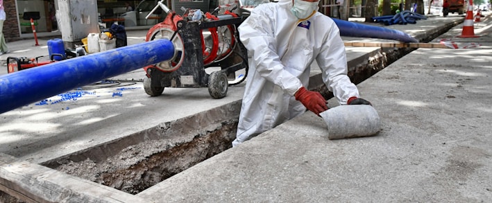 a man wearing a protective suit and a hard hat working on a street