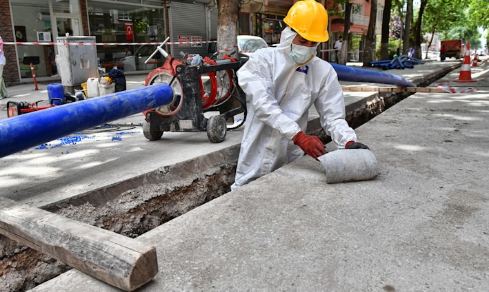 a man wearing a protective suit and a hard hat working on a street