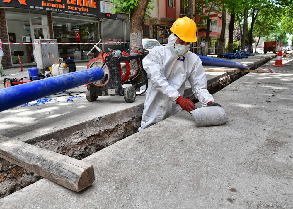 a man wearing a protective suit and a hard hat working on a street