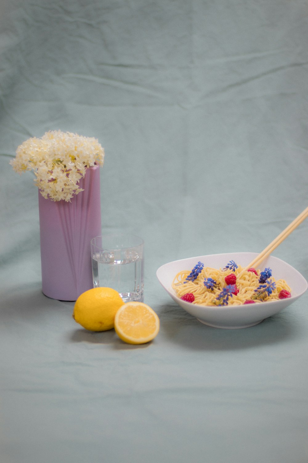 white and yellow flower bouquet beside clear glass vase with lemon