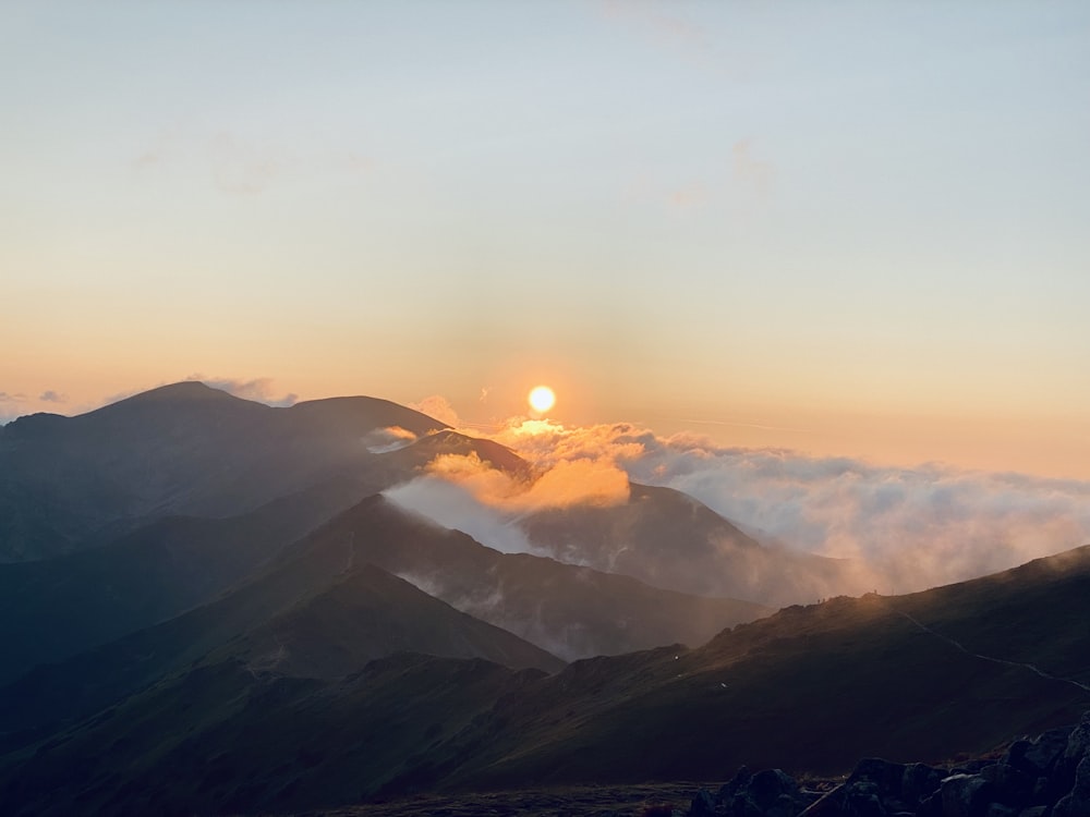 the sun is setting over a mountain range