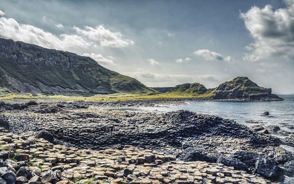 brown rocky shore near mountain under white cloudy sky during daytime