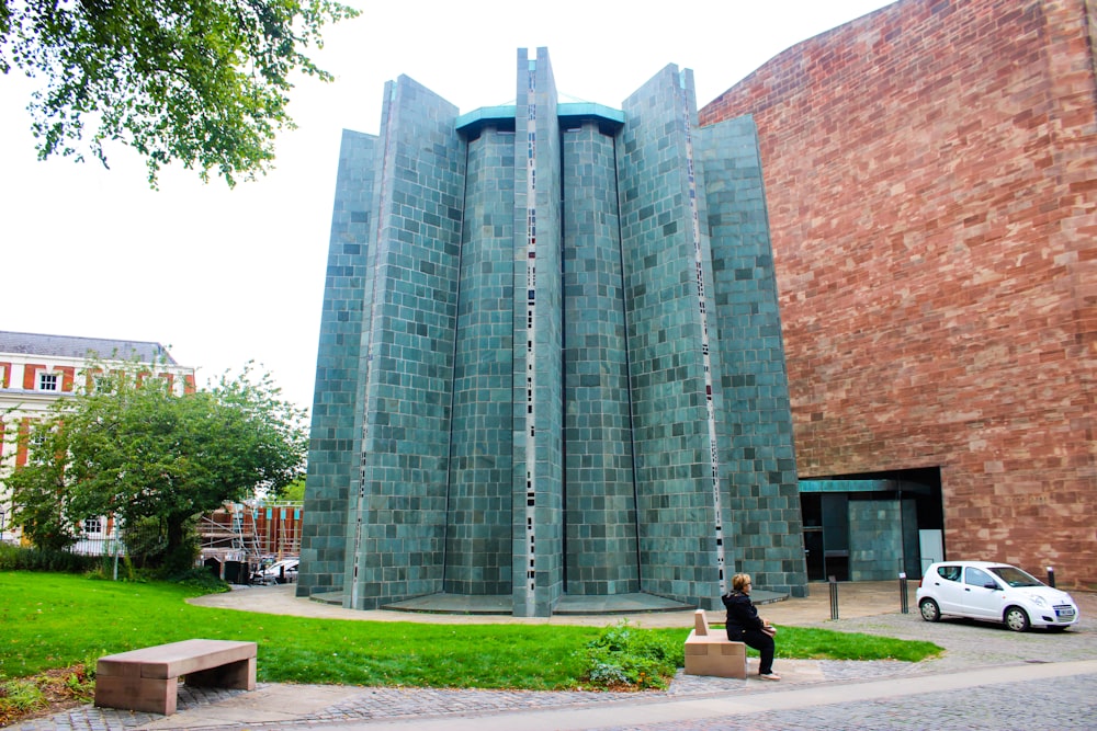 a woman walking past a tall building next to a park