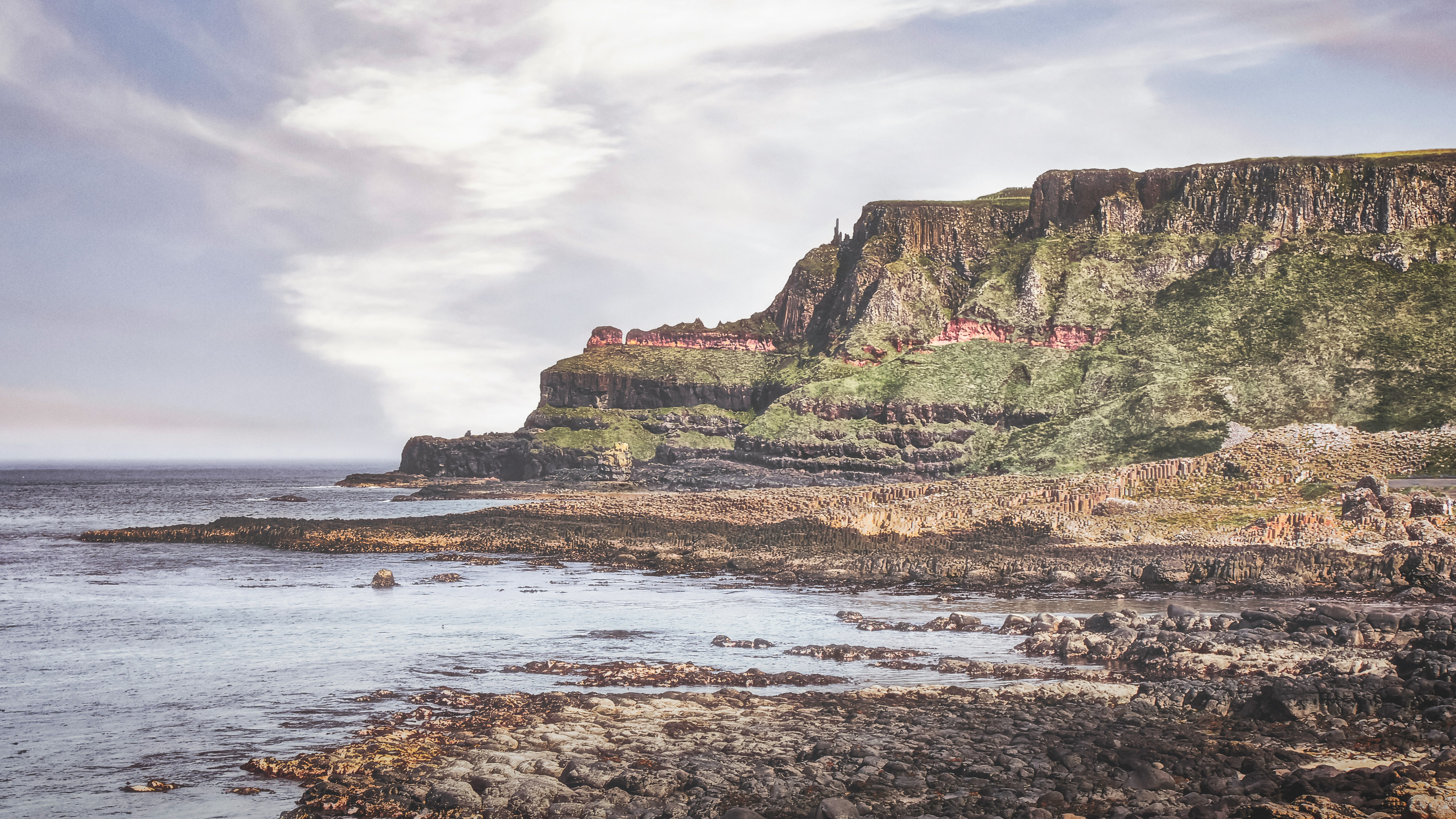 brown and green rock formation on sea shore during daytime