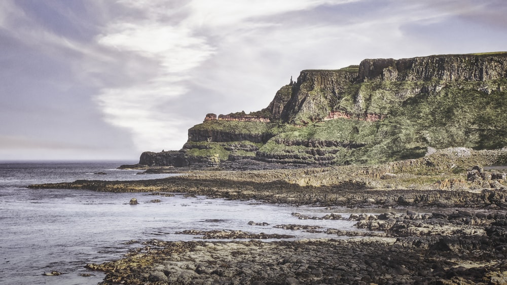 brown and green rock formation on sea shore during daytime