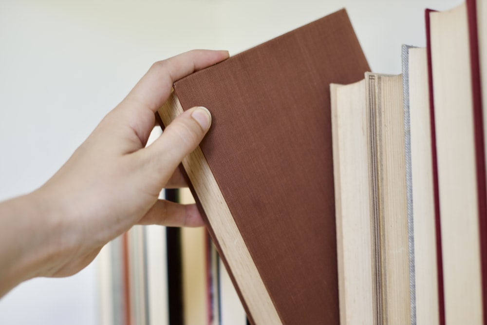 a person holding a book in front of a stack of books