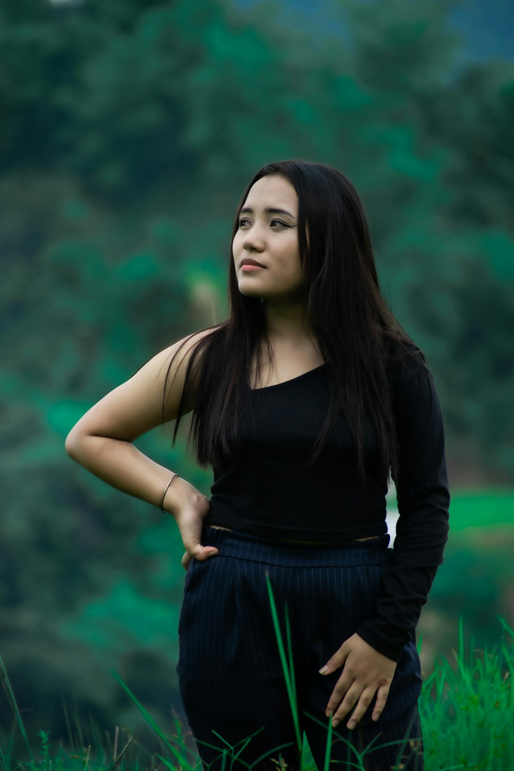 a woman standing in the grass with her hands on her hips