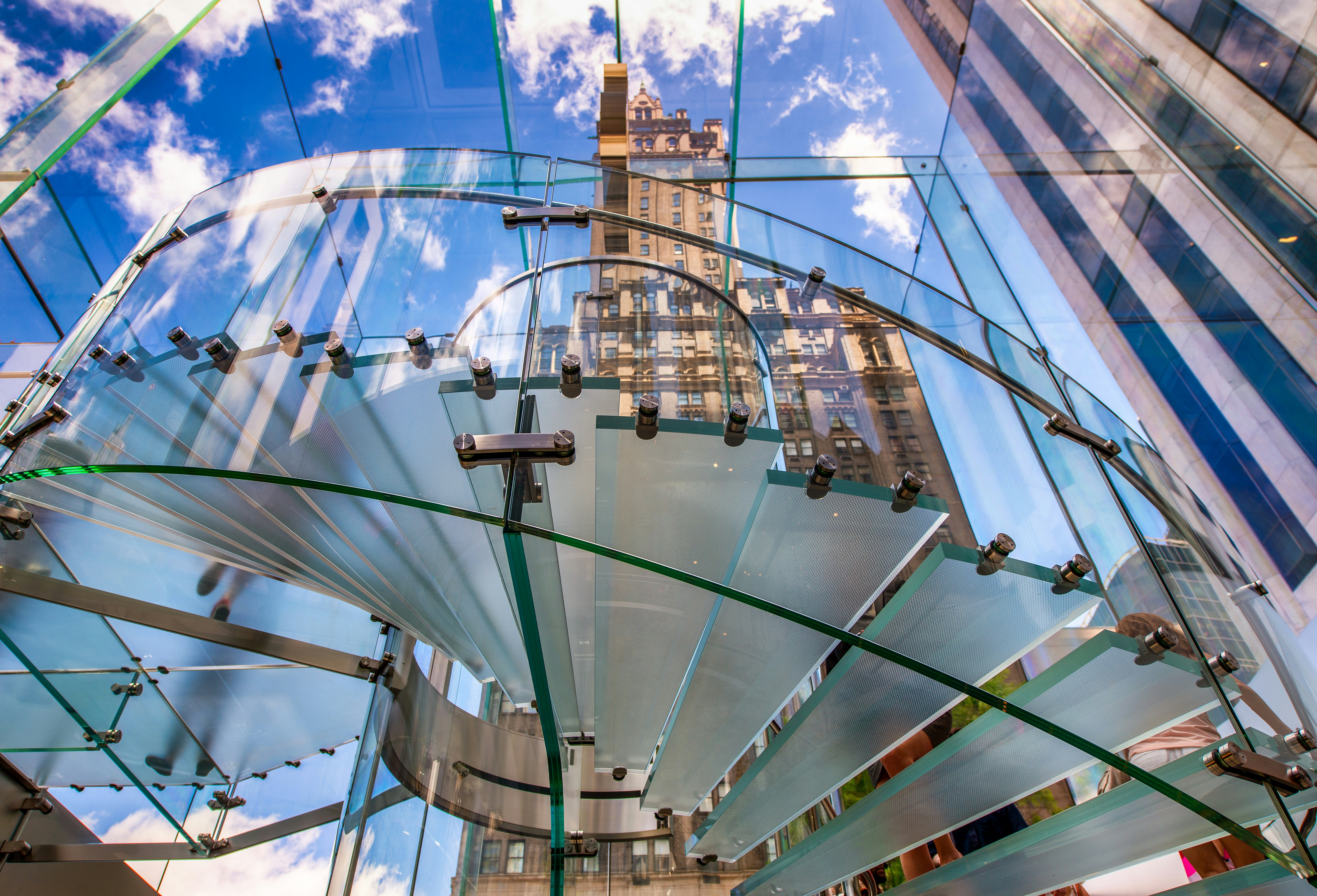 a glass structure with a clock tower in the background