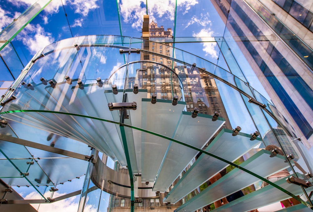 a glass structure with a clock tower in the background