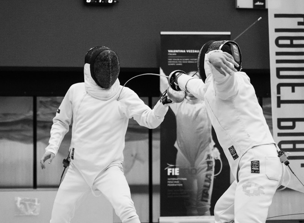 two men in white fencing suits playing a game of fencing